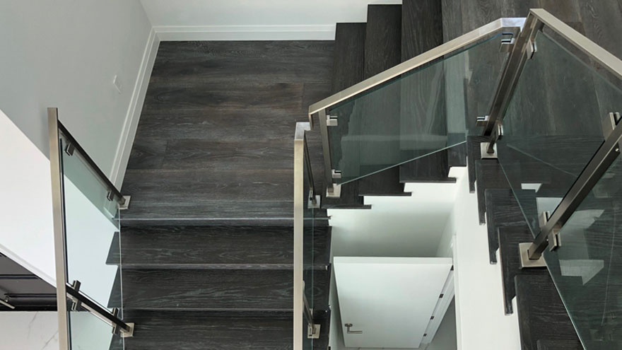 Glass railing system. Glass panel railing on switchback stairs installed as a home railing system.