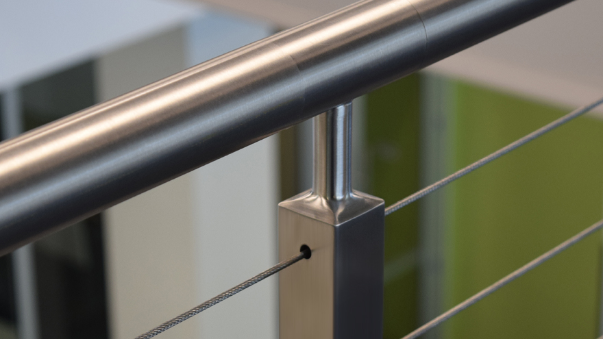 Brushed stainless railing post with cable infill.