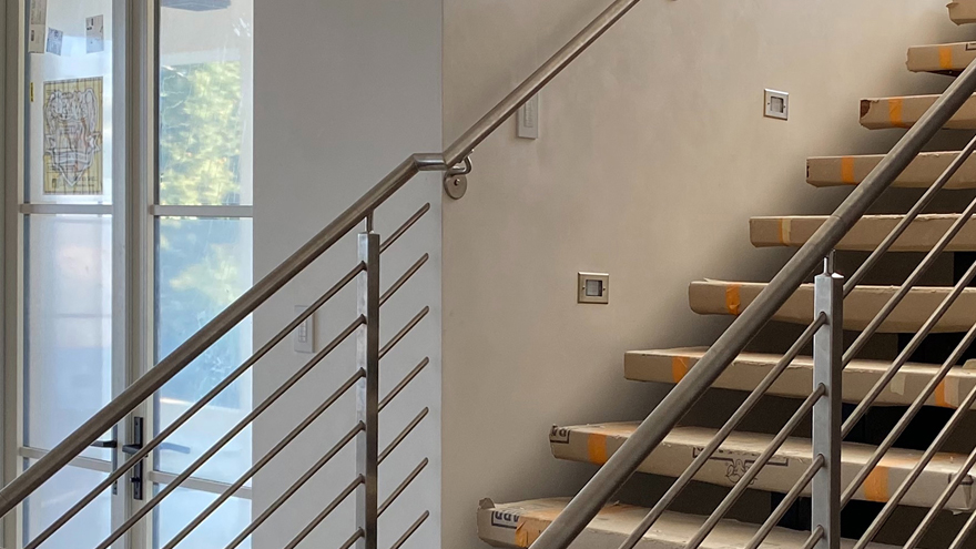 Horizontal railing system on enclosed stairs with custom metal handrail.