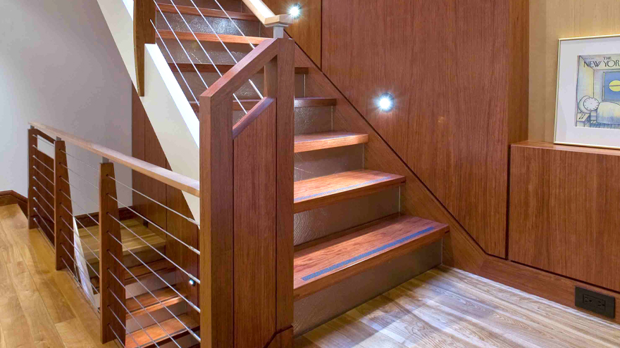 Wood and wire railing on stairway. Custom wood newel post with cable infill creates a modern home railing.