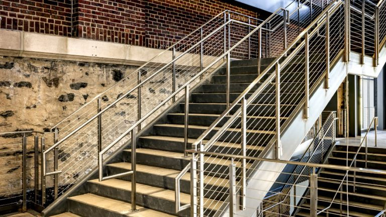 Commercial stair railing with handrail returns and extensions.