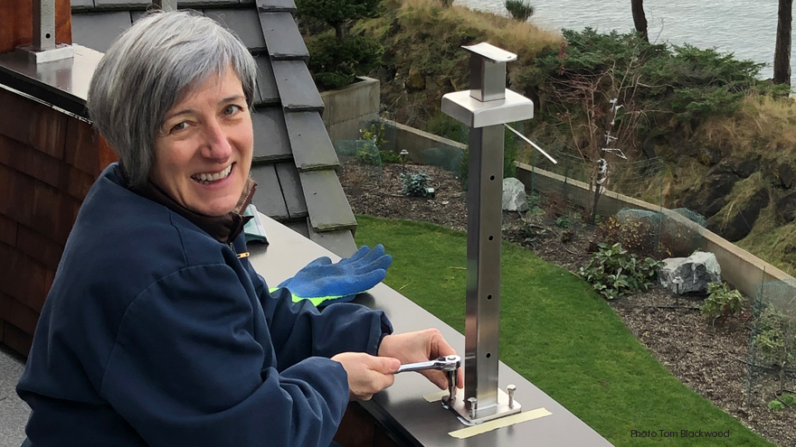 A homeowner installing a custom balcony railing system on a pony wall.