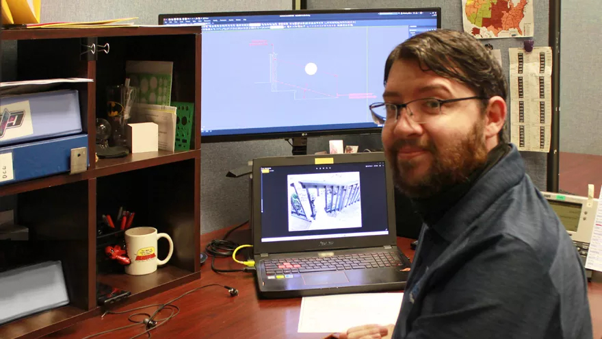 Lead railing system designer Cody sits at his desk.