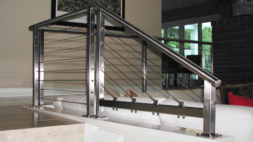 Custom stair railing on a half wall. Bespoke cable railing solution for modern home.
