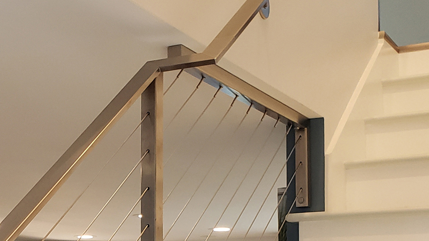 flat metal handrail transitions from being wall-mounted to post mounted.