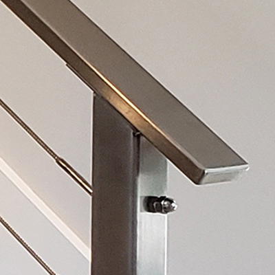 Flat stainless handrail sits atop a stainless steel cable railing post.