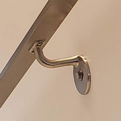Flat metal handrail mounted to a wire railing system using a wall-mounted bracket.