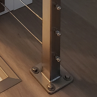 railing post with base plate mounted on top of the floor surface.