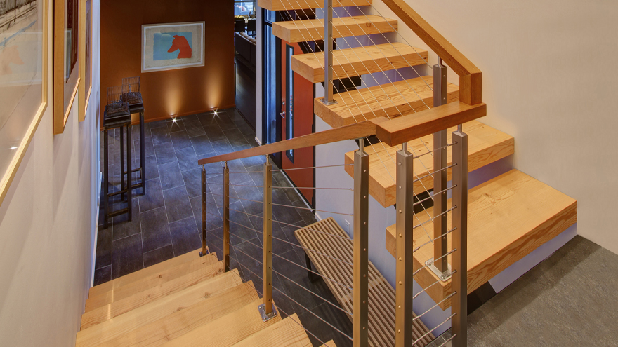 Wire railing on steps. Switchback staircase with open risers, and cable rail.