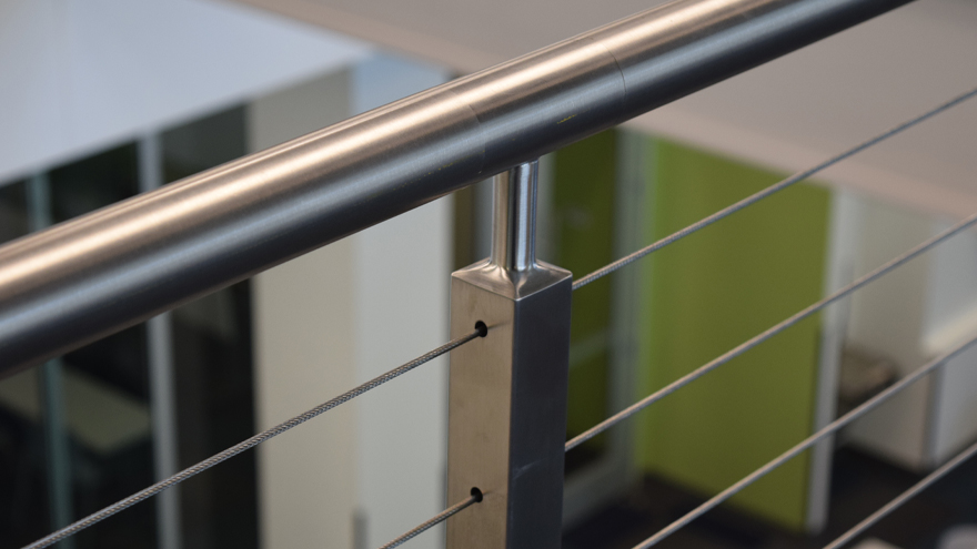 Round metal handrail and post top detail create a unique modern railing design.