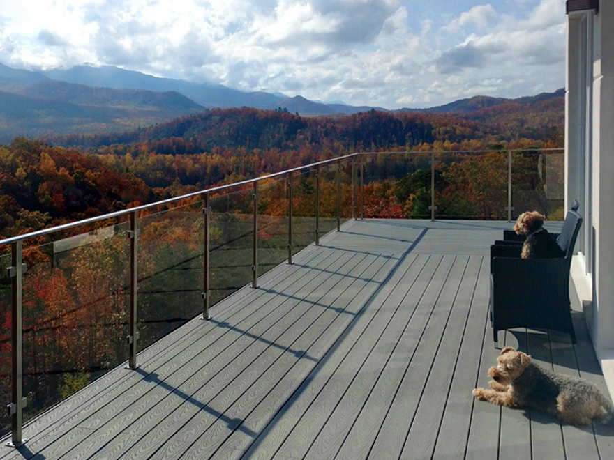 Modern glass railing design installed on a luxury deck. Glass deck railing systems enable the resident to enjoy the view. A glass and metal railing is a great choice for a see-through deck railing design.