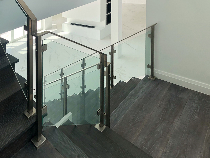 Staircase glass railing creates a modern aesthetic. A glass banister with glass railing posts looks stunning.