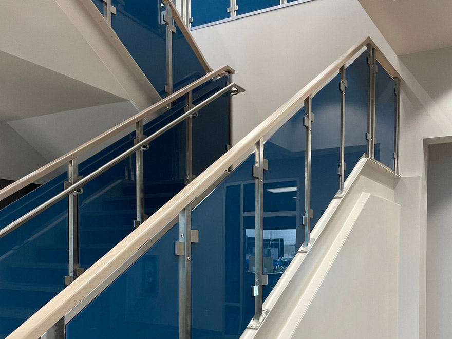 Custom glass handrail design with blue glass panel infill. The glass guard rail is made from wood and the grab rail is stainless steel.