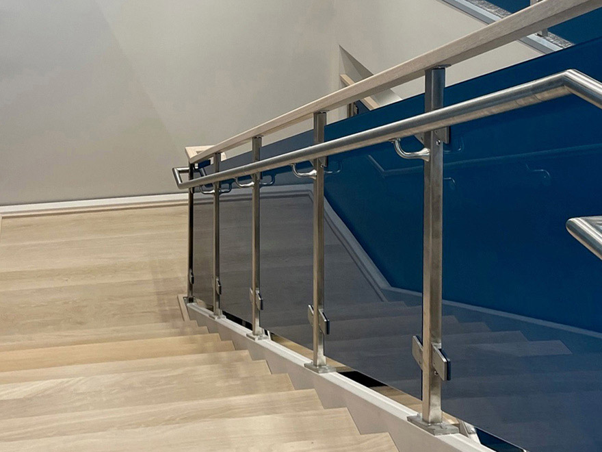 Glass stair color railing design for commercial building. Wood cap rail and stainless grab rail.