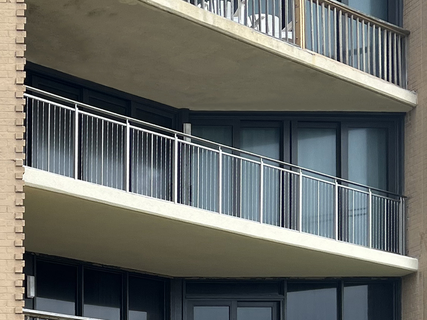 Vertical metal balusters on a balcony for commercial railing installation on an office building.